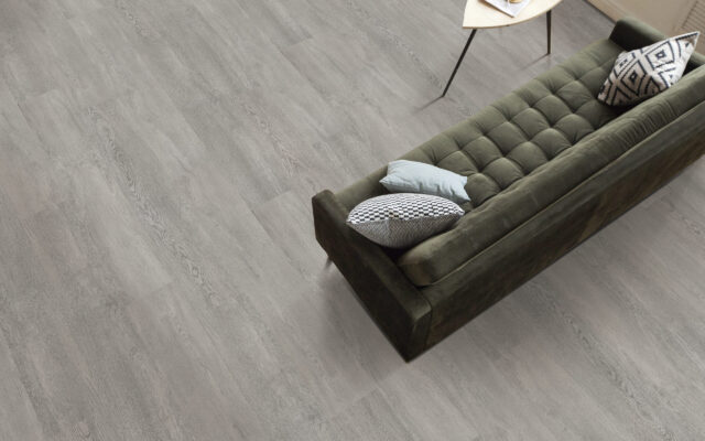 From above shot of comfortable couch and small table standing on wooden floor in spacious living room